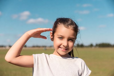 Girl saluting in green field