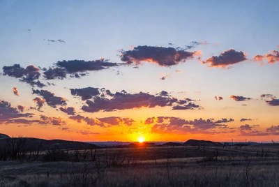 Sunset over grassy field with hills