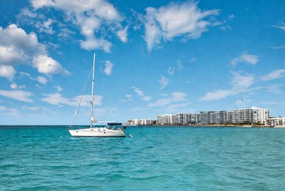White Sailboat in Turquoise Sea with Beachfront Buildings