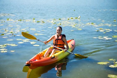 Woman paddling kayak in lily pads