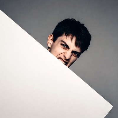Angry man peeking over white sign