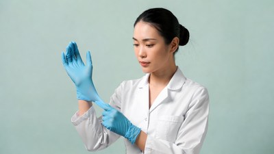 Asian woman putting on blue gloves