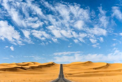 Straight road through golden sand dunes