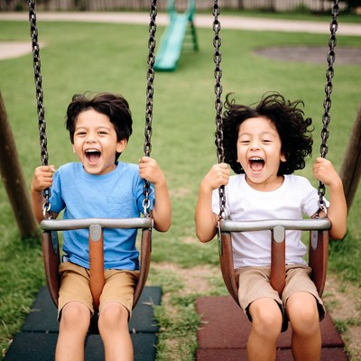 Two boys swinging on playground swings