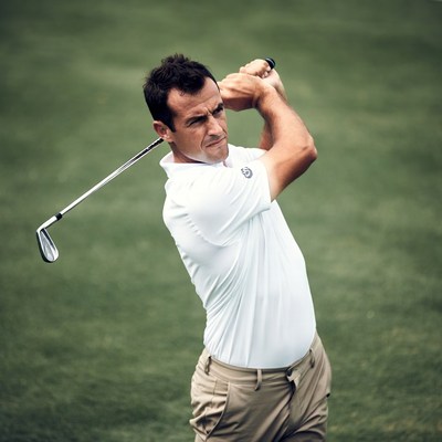 Man swinging golf club on green