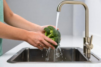 Woman washing broccoli under faucet