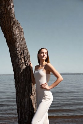 Woman leaning against tree by lake