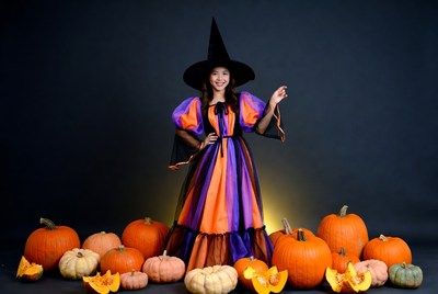 Asian woman in witch costume with pumpkins