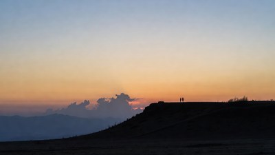 Silhouette couple on cliff at sunset