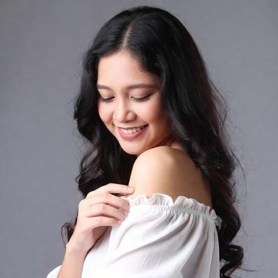 Asian woman smiling in off-shoulder dress