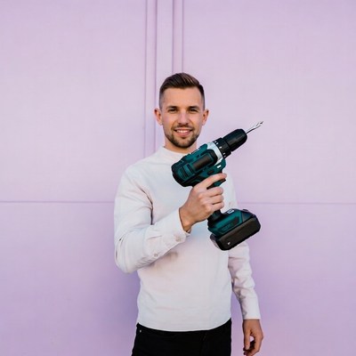 Man holding drill against purple wall