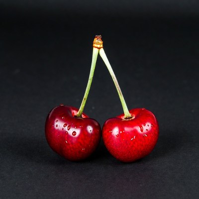 Two Red Cherries on Black Background