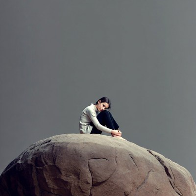 Asian woman sitting on large rock