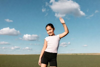 Asian girl waving in green field