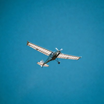 White small plane flying in blue sky