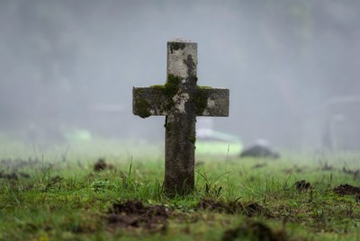 Mossy wooden cross in foggy cemetery