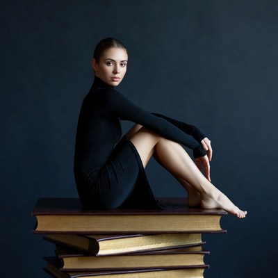 Woman sitting on stack of books