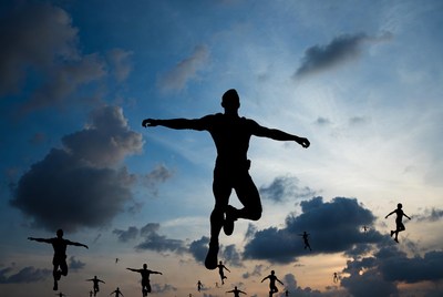 Silhouette people jumping against sunset sky