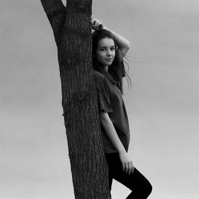 Young woman leaning against tree