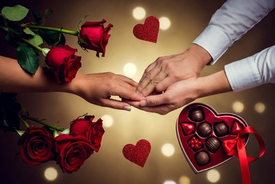 Couple's hands holding chocolates and roses