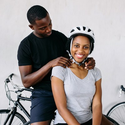 Man helping woman put on bike helmet