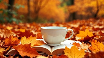 White Cup and Open Book on Autumn Leaves
