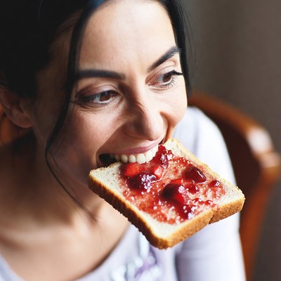Woman eating strawberry jam toast