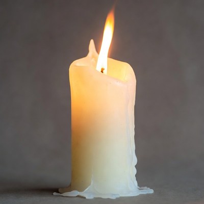 Burning white candle with dripping wax