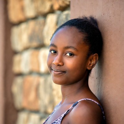 African girl smiling against stone wall