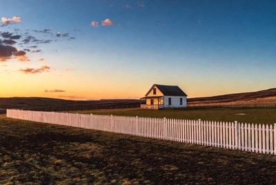 White farmhouse at sunset with picket fence