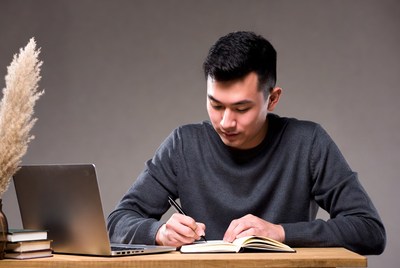 Asian man writing in notebook