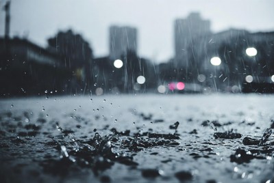 Rain drops on wet pavement with city skyline