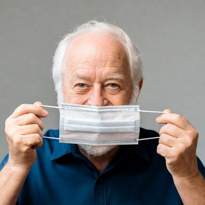 Elderly man holding face mask