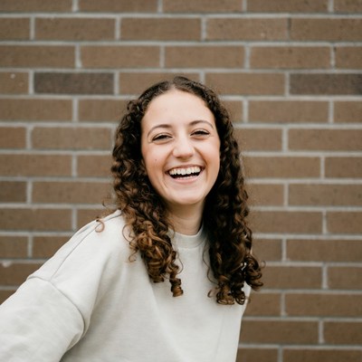 Smiling woman with curly hair against brick wall