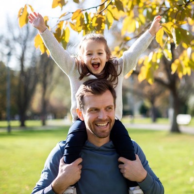 Father carrying smiling daughter on shoulders
