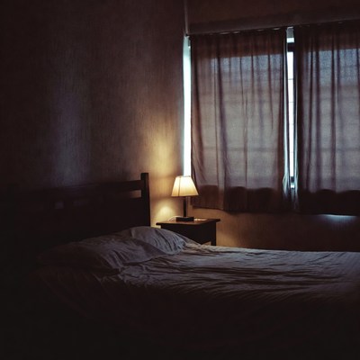 Empty Bed with Lamp in Dim Bedroom