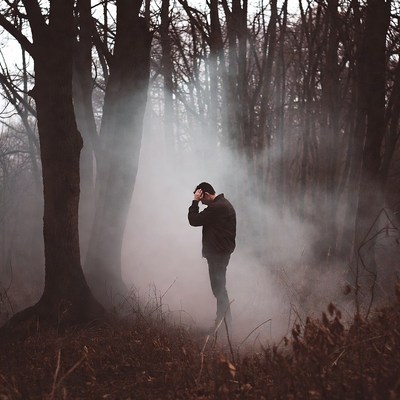 Man covering face in foggy forest