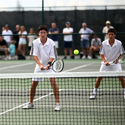 Two boys playing tennis doubles match
