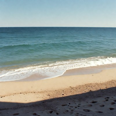 Sandy Beach with Waves and Footprints