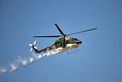 Camouflaged Helicopter Flying with Smoke Trail