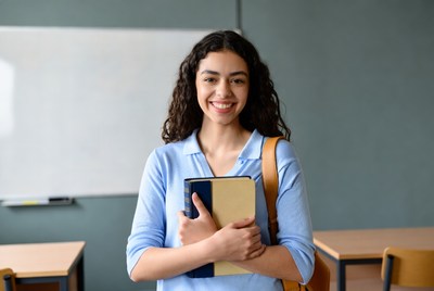 Smiling woman holding book in classroom