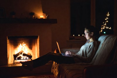 Woman working on laptop by fireplace