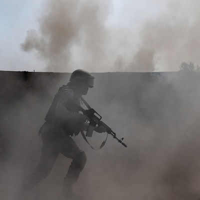 Soldier running with rifle in smoke