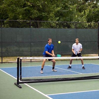 Two men playing pickleball over net