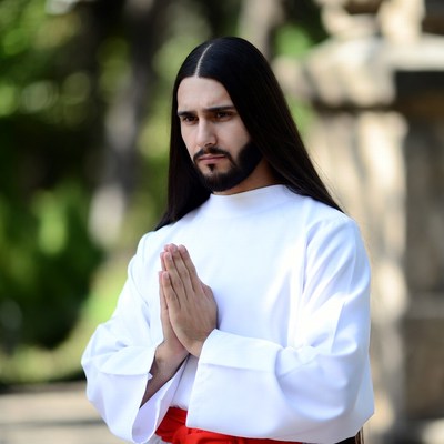 Man Praying with Hands in White Robe