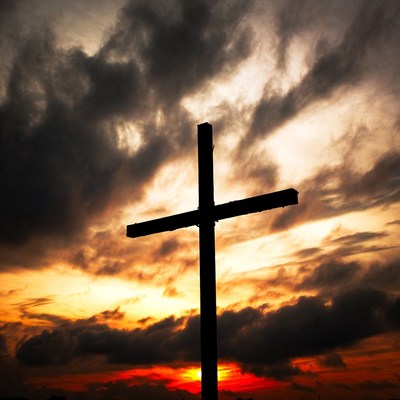 Silhouette cross against sunset clouds