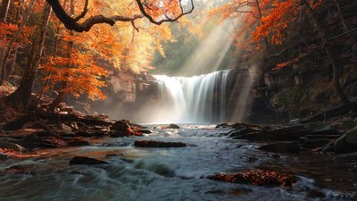 Waterfall in Autumn Forest with Sunbeams