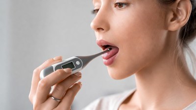 Woman taking temperature with thermometer