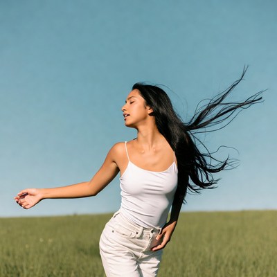 Asian woman dancing in green field