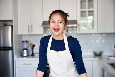 Asian woman smiling in kitchen apron